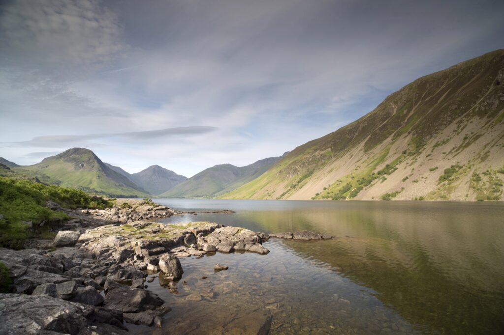 Rocky lakeshore with steep hills beneath clouds in the Lake District