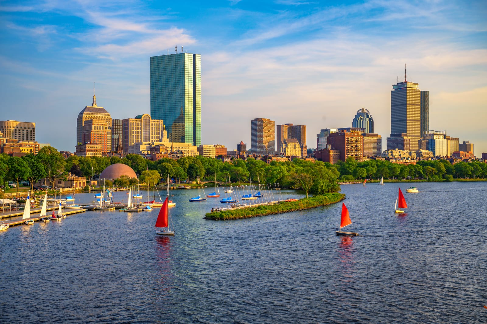 Sailing boats on the Charles River with Boston's skyline and riverside trees behind them
