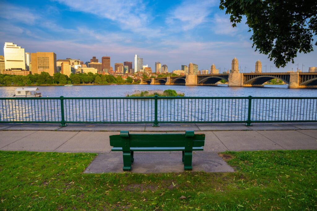 Bench beside the Charles River with Boston's skyline and a bridge in the distance