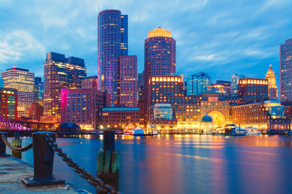 Illuminated buildings along Boston's waterfront reflected in the water at dusk