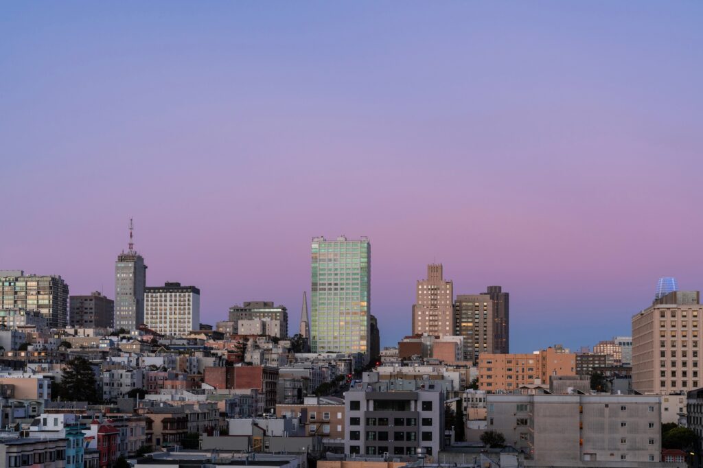 View over San Francisco buildings and hills beneath a pink evening sky