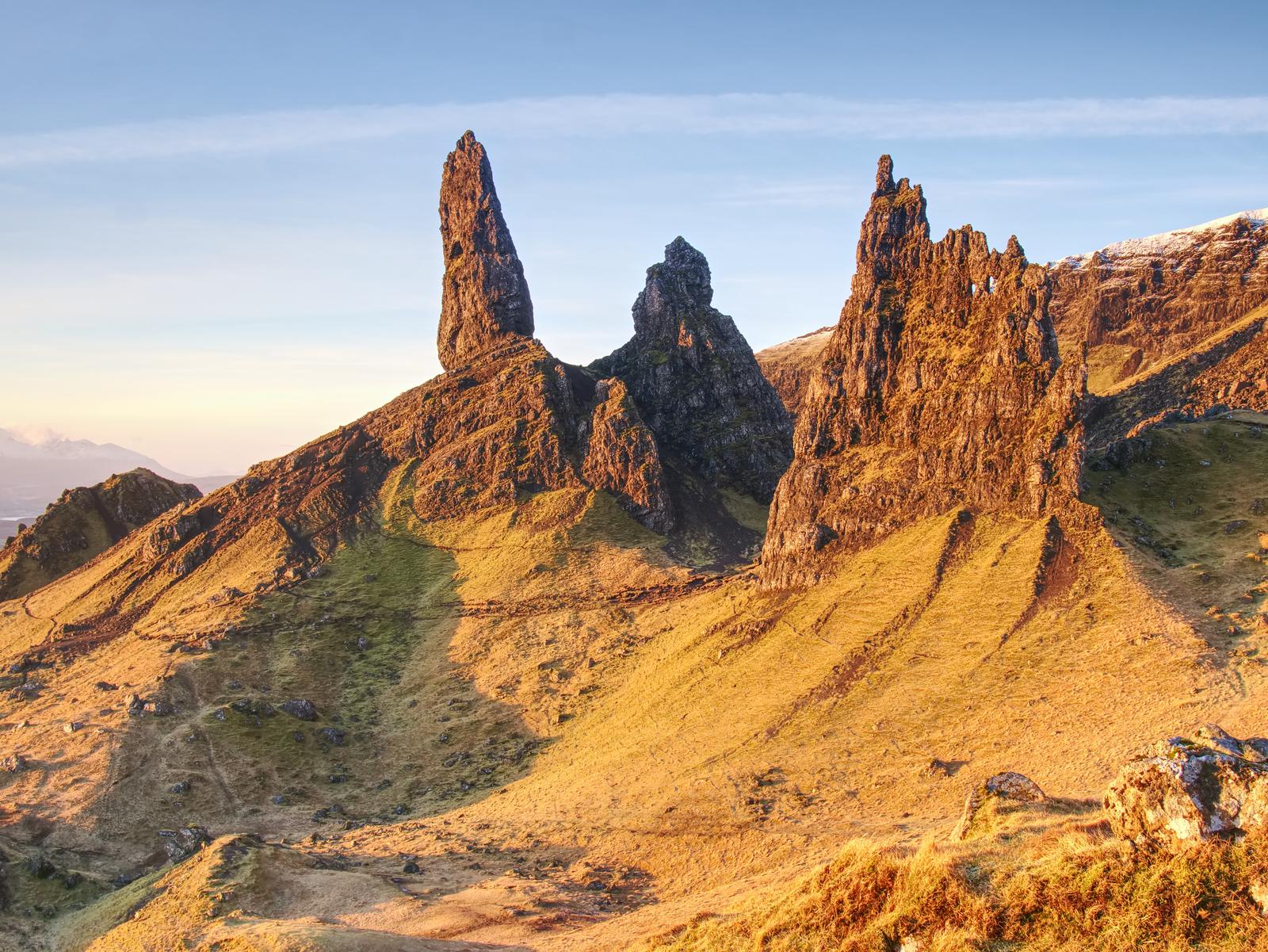 Rock pinnacles of the Old Man of Storr above sunlit slopes on the Isle of Skye