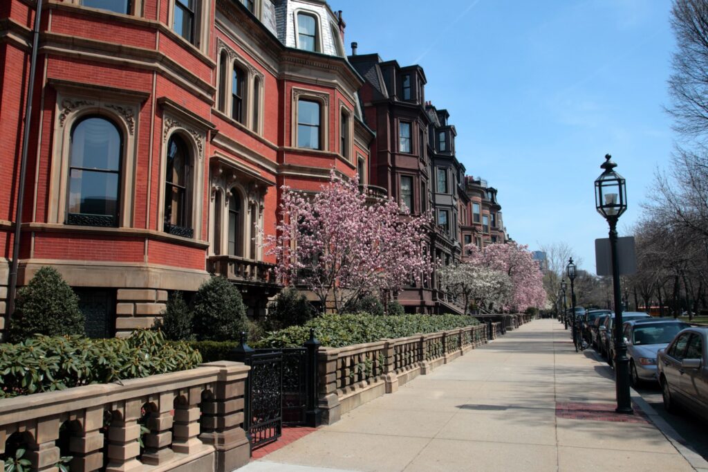 Brick houses, flowering trees and railings along a pavement in Back Bay