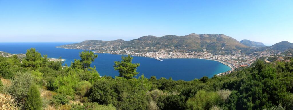 Wide view of a bay on Samos with wooded slopes and buildings along the coast