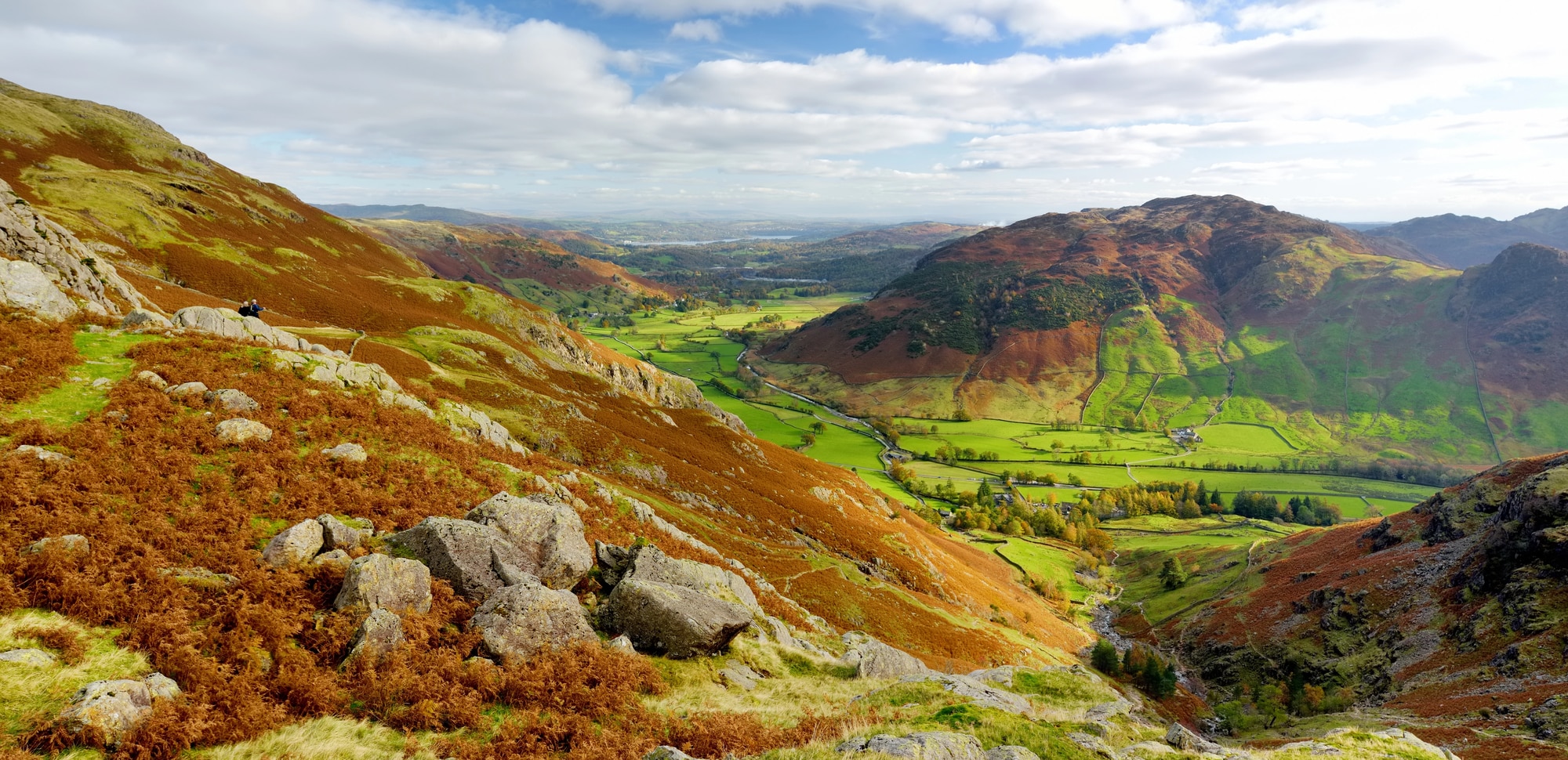 Rocky hillside with autumn bracken above a green valley and hills in the Lake District