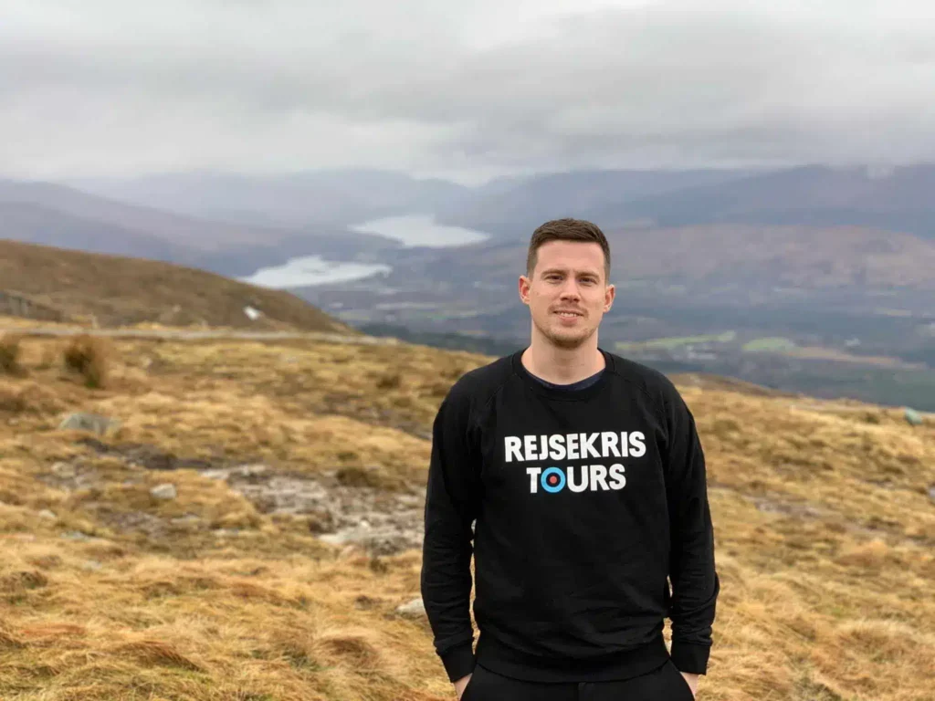 Kristoffer Fons from Destination Well Known on a grassy hillside with mountains in the distance near Fort William