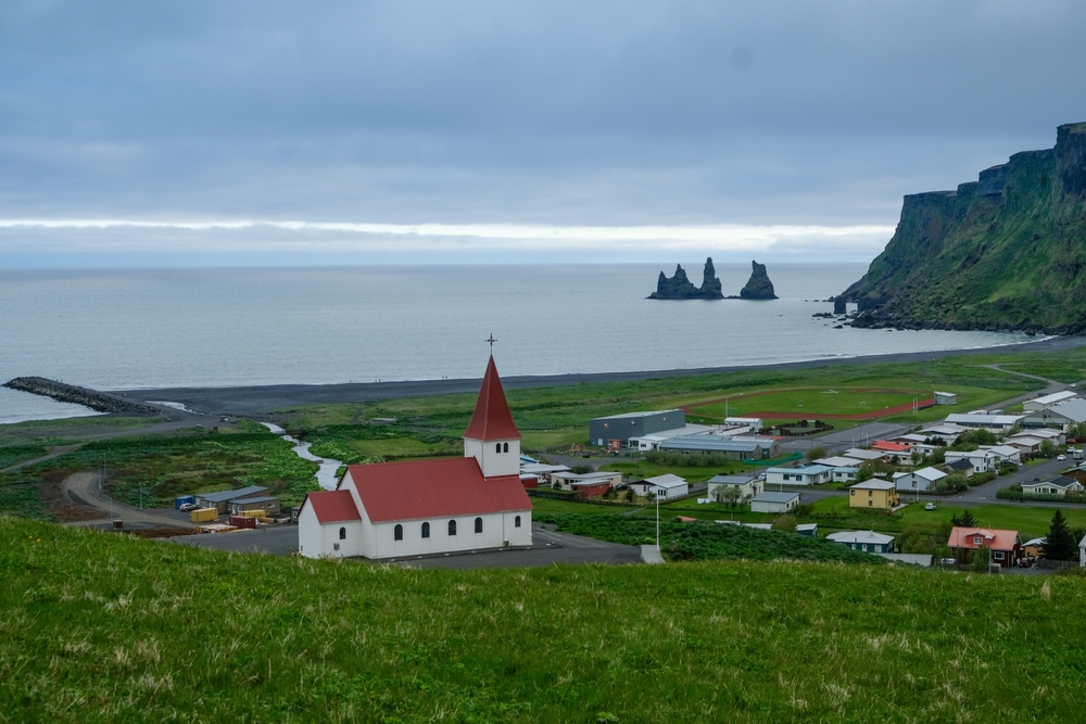 Vík with its church, the black sand beach and the Reynisdrangar sea stacks on the South Coast of Iceland