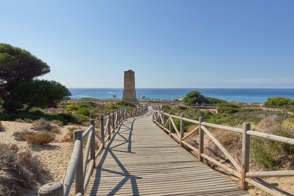 Boardwalk through the Dunas de Artola dunes at Cabopino with the Torre de los Ladrones watchtower