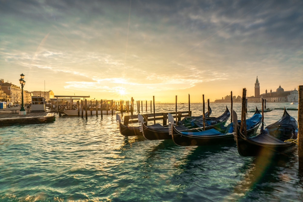 Gondolas moored along the waterfront in Venice at sunset