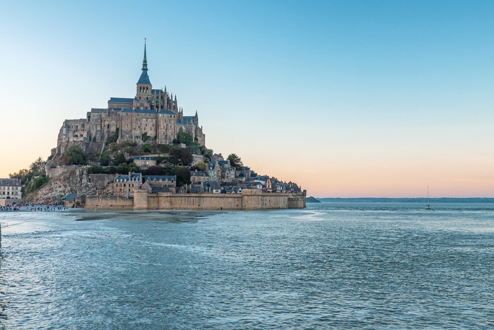 Mont-Saint-Michel surrounded by water at high tide at sunset
