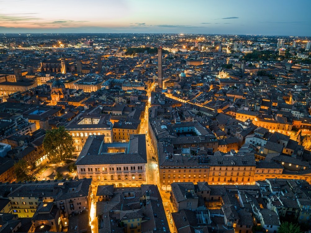 Aerial view of Bologna's red rooftops and medieval towers at dusk