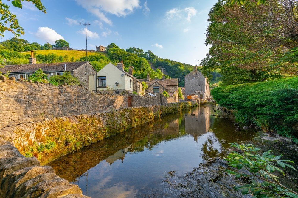 The village of Castleton and its stream with the ruins of Peveril Castle above the houses