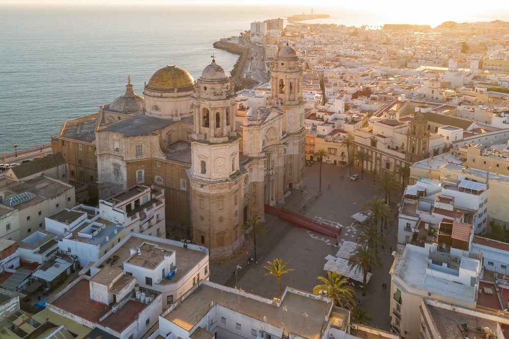 Aerial photo of the cathedral and Old Town in Cádiz at sunset, with the Atlantic Ocean behind