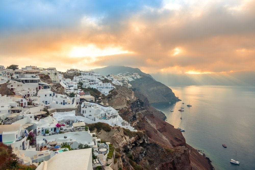 yachts and catamarans at anchor below Oia at dawn